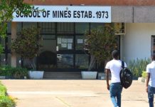 a picture of 3 maile zambia students walking up to the entrance of the school of mines which was established in 1973